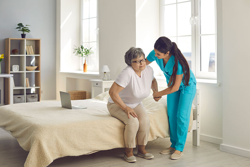 Female caregiver who cares for an elderly woman in a nursing home helps