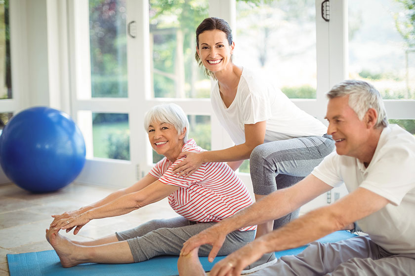 Female trainer assisting senior couple in performing exercise Female trainer assisting senior couple in performing exercise