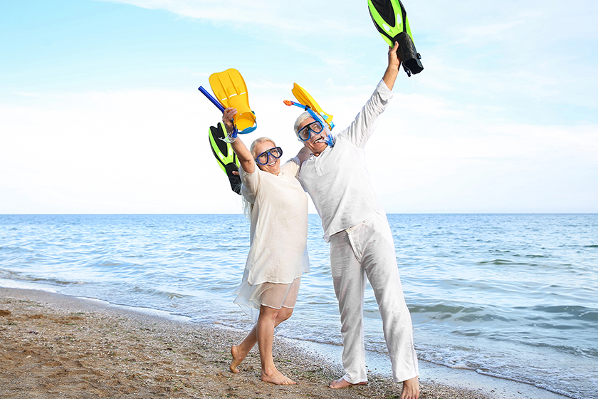 happy mature couple with snorkeling masks and paddles