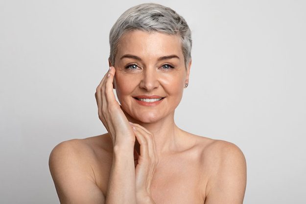 Nude portrait of beautiful mature woman over light background closeup Nude portrait of beautiful mature woman over light background closeup