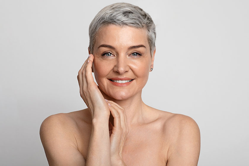 Nude portrait of beautiful mature woman over light background closeup