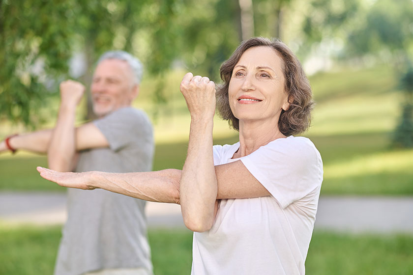 People having a yoga class in the park and stretching their arms People having a yoga class in the park and stretching their arms