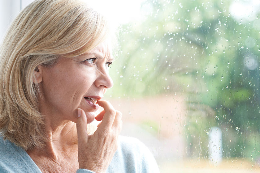 Sad mature woman suffering from agoraphobia looking out of windo