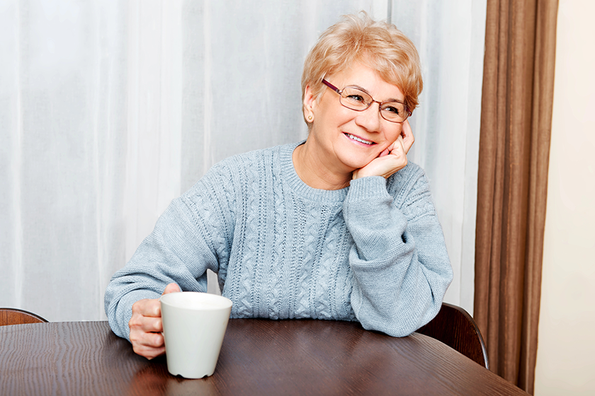 senior woman sitting at the desk and drinking coffee