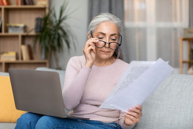 Serious caucasian old gray haired lady glasses works documents laptop Serious caucasian old gray haired lady glasses works documents laptop