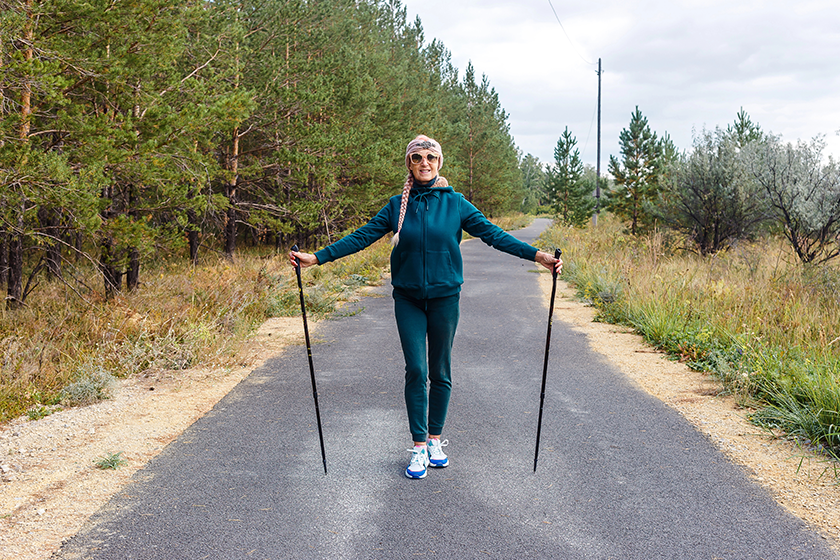 happy elderly woman green tracksuit holding poles