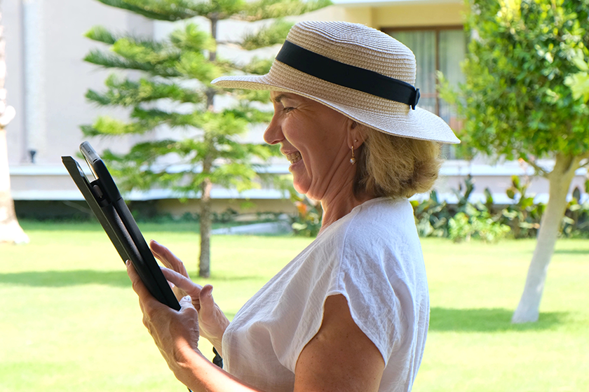 senior female blonde businesswoman in hat uses tablet pc