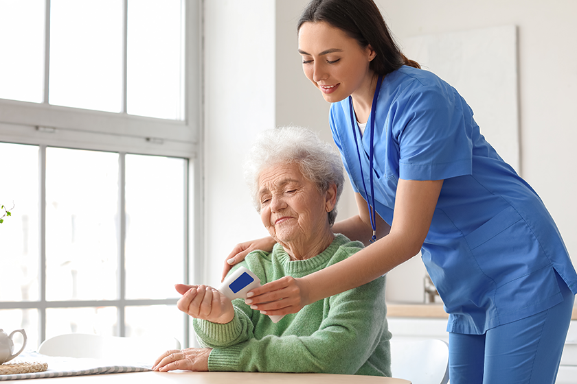 young caregiver measuring temperature senior woman