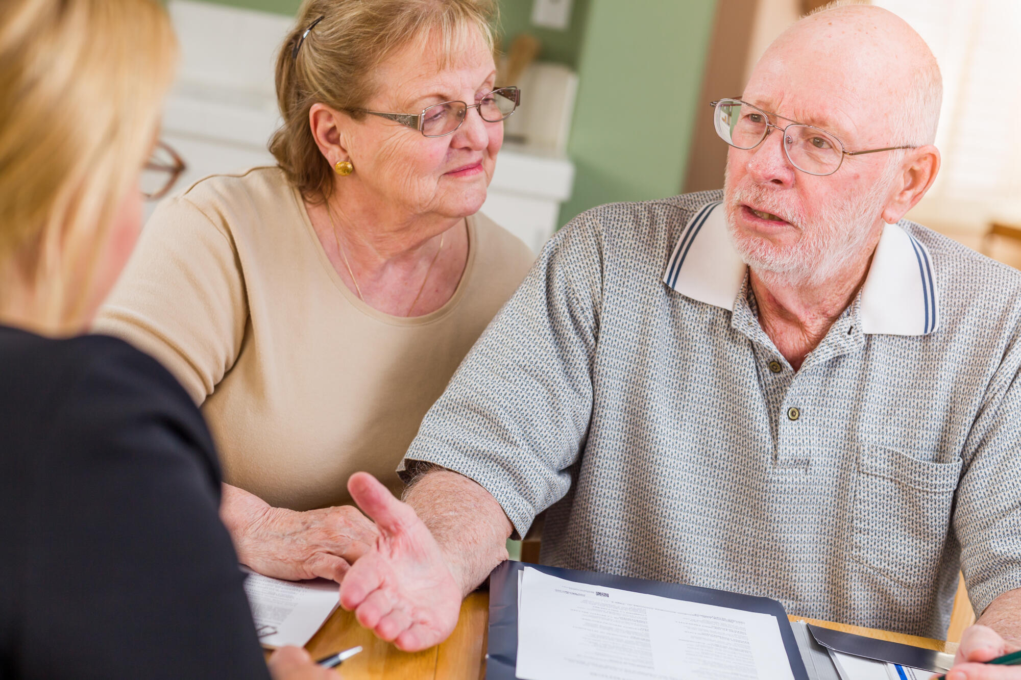 Senior Adult Couple Going Over Documents in Their Home with Agent At Signing. Senior Adult Couple Going Over Documents in Their Home with Agent At Signing.