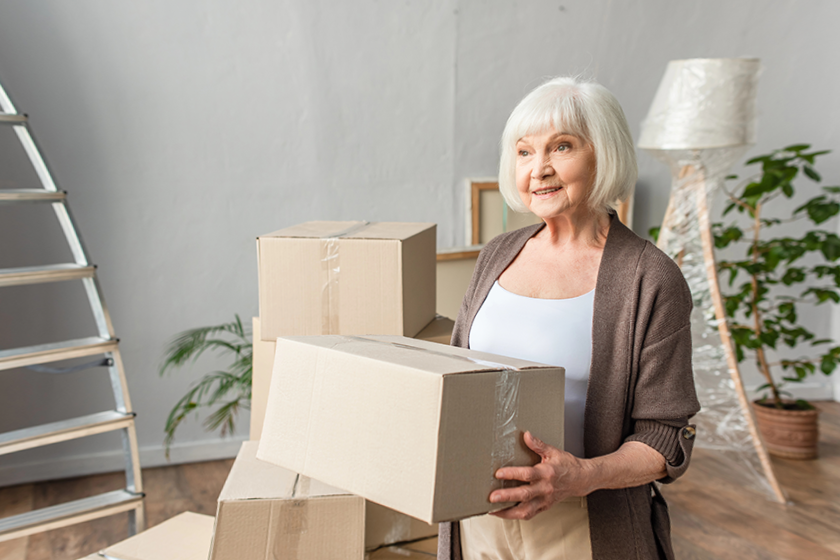 cheerful senior woman holding cardboard box