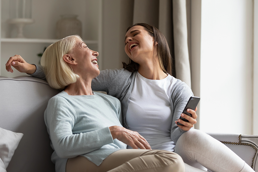 happy elderly mother and adult daughter using smartphone