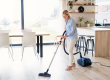 portrait of senior woman with vacuum cleaner indoors