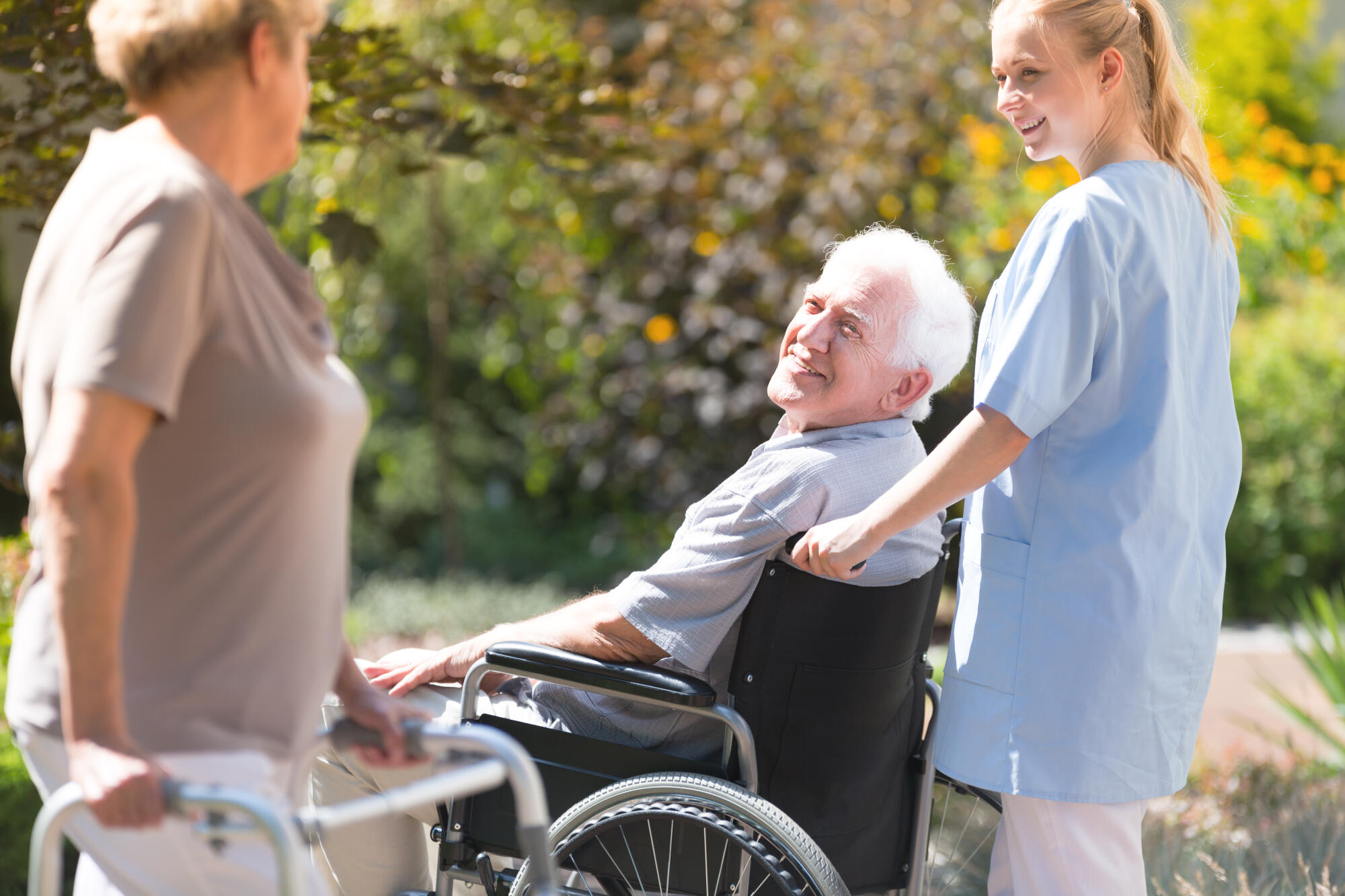 Disabled,Elder,In,Wheelchair,Spending,Time,Outdoors,With,Young,Nurse