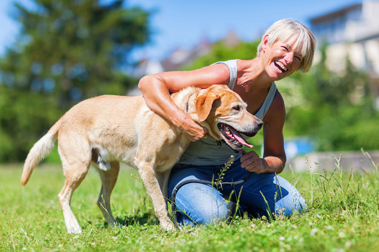 happy mature woman plays with a dog