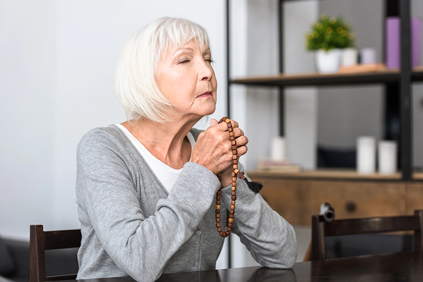 senior woman holding wooden rosary
