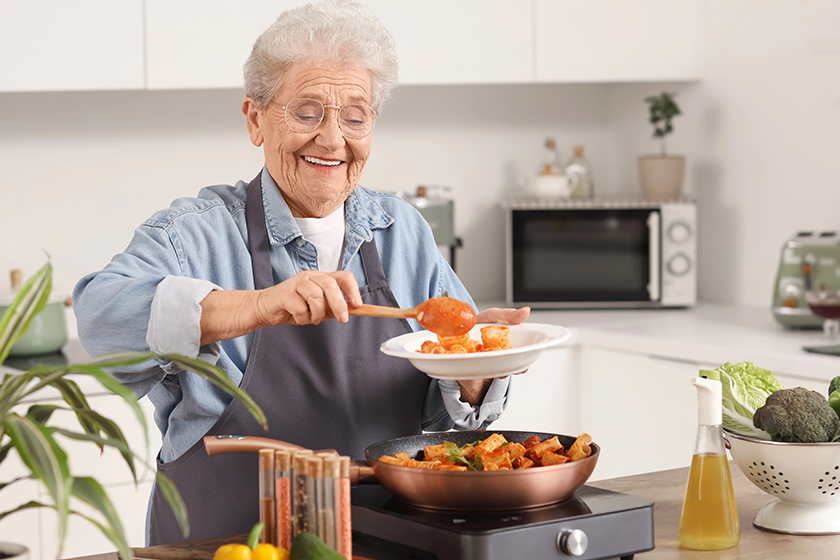 senior woman putting fried pasta senior woman putting fried pasta