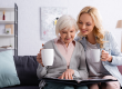 smiling elderly woman cup looking photo album