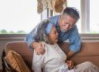 Elderly asian carrying his wife in pain lying on sofa in living