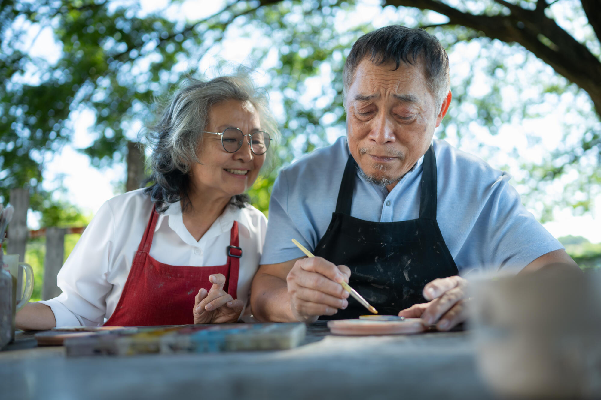 In the pottery workshop, an Asian retired couple is engaged in p
