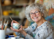 joyful senior woman engaged in painting a cup