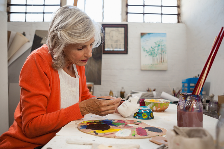 senior woman painting bowl
