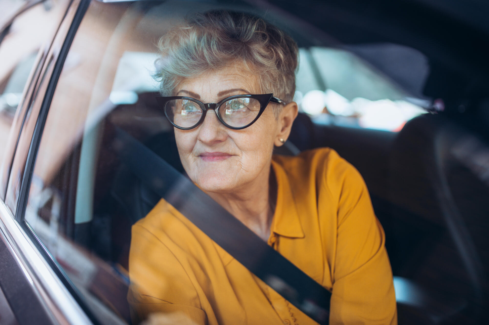 Senior,Woman,With,Glasses,Sitting,In,A,Car.,Shot,Through