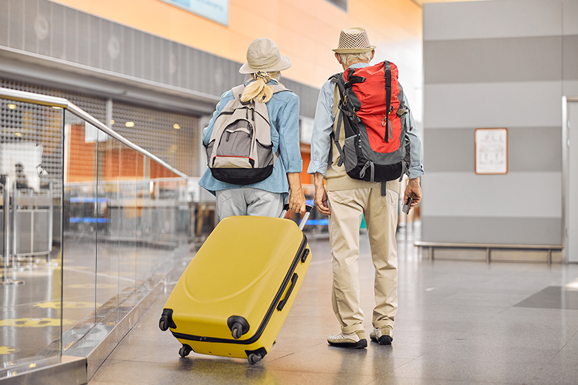 two caucasian elderly travelers standing at the airport