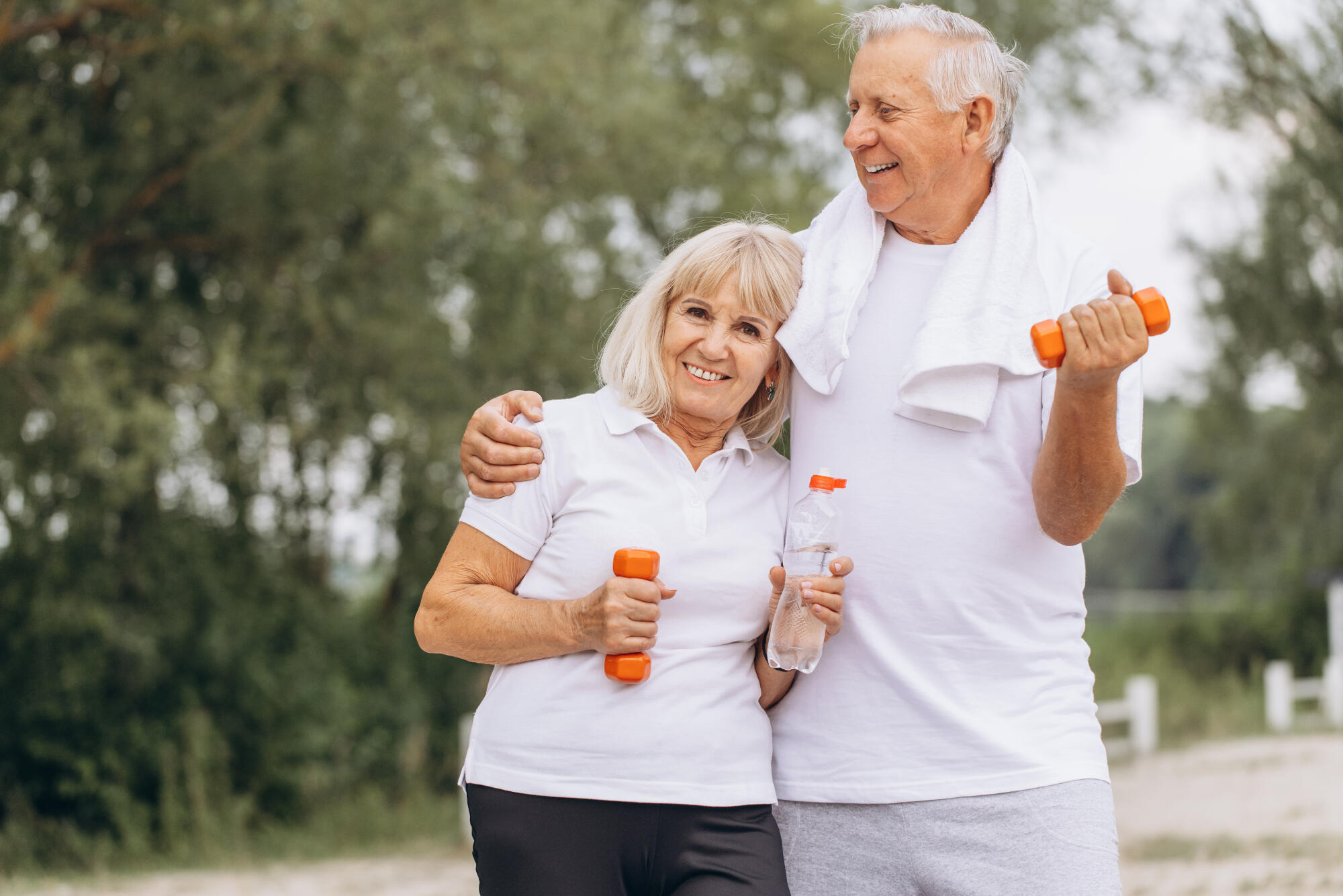 Happy Senior Couple Exercising Outdoors with Dumbbells and Water